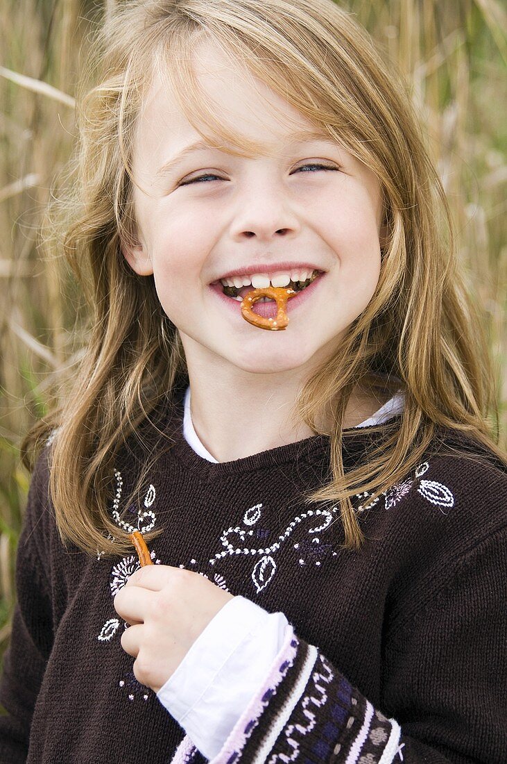 Smiling girl with salted pretzel in her mouth