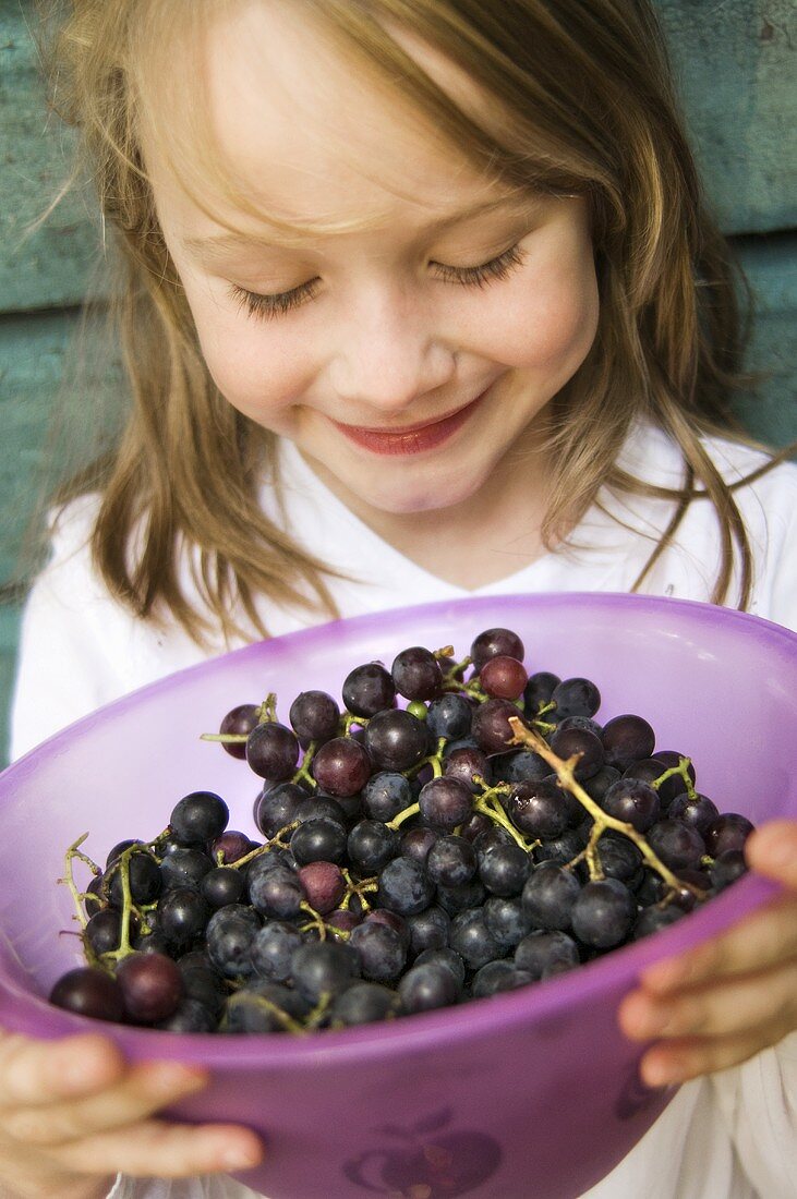 Girl holding a bowl of grapes