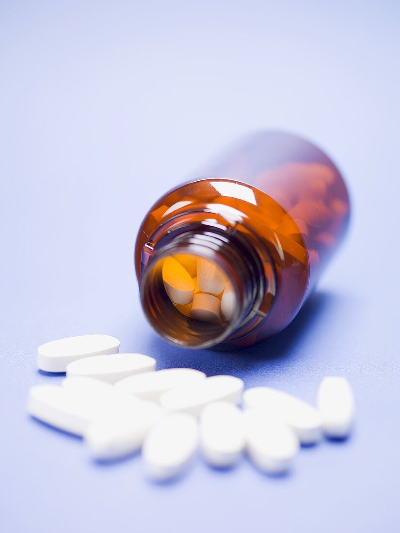 Tabletten im umgekippten Medizinglas und davor