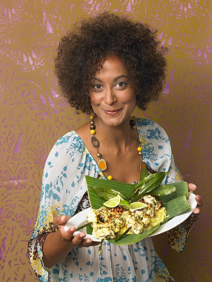 Young woman with spicy fish kebabs in banana leaf
