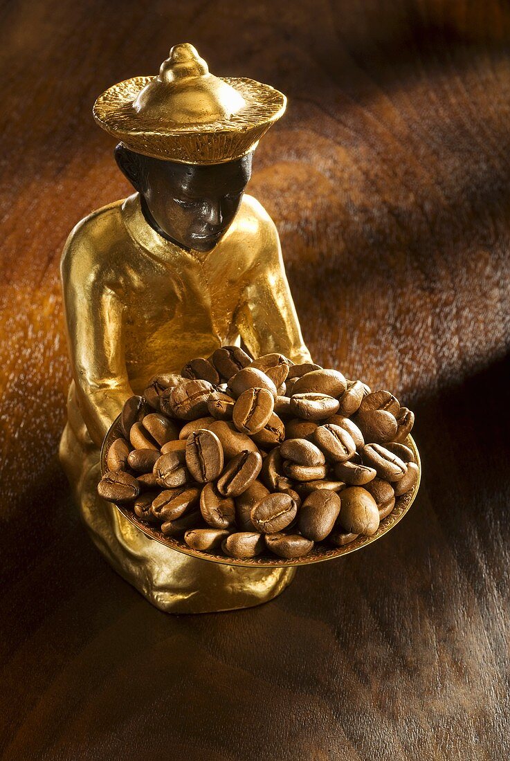 Gilded statuette with a bowl of coffee beans