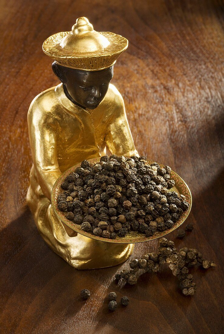 Gilded statuette with a bowl of black pepper