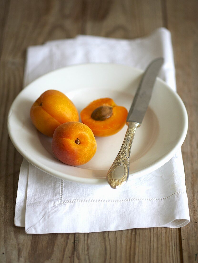 Aprikosen mit Messer auf einem Teller