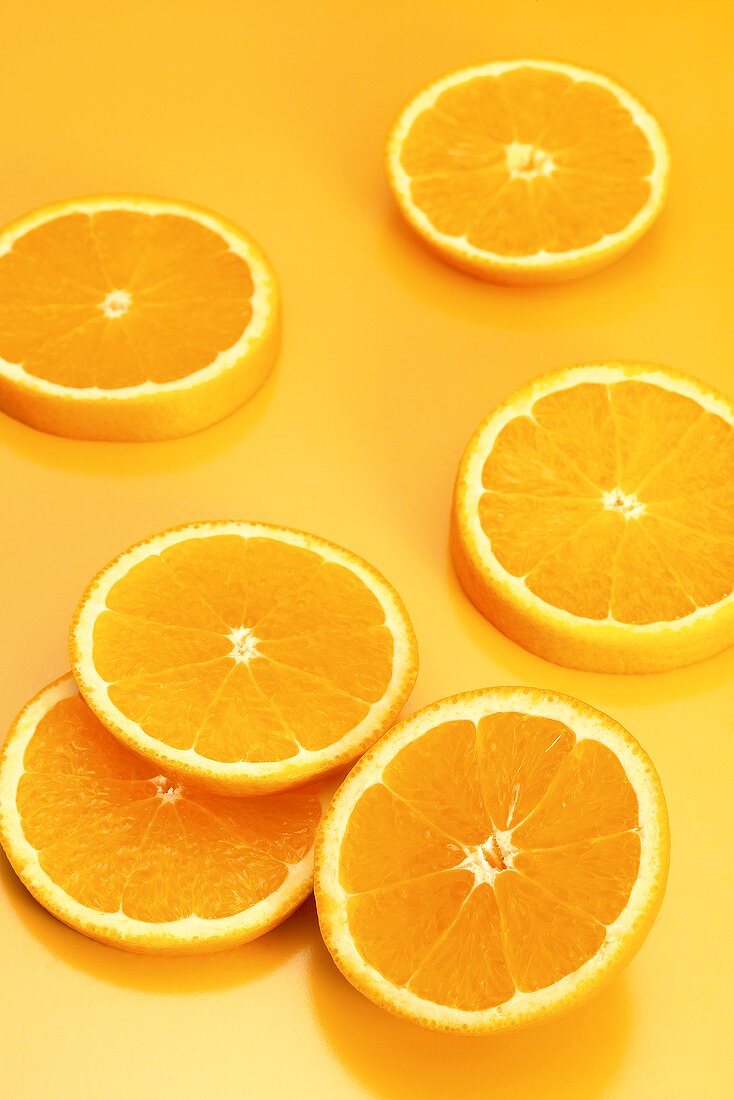 Mehrere Orangenscheiben auf orangefarbenem Hintergrund