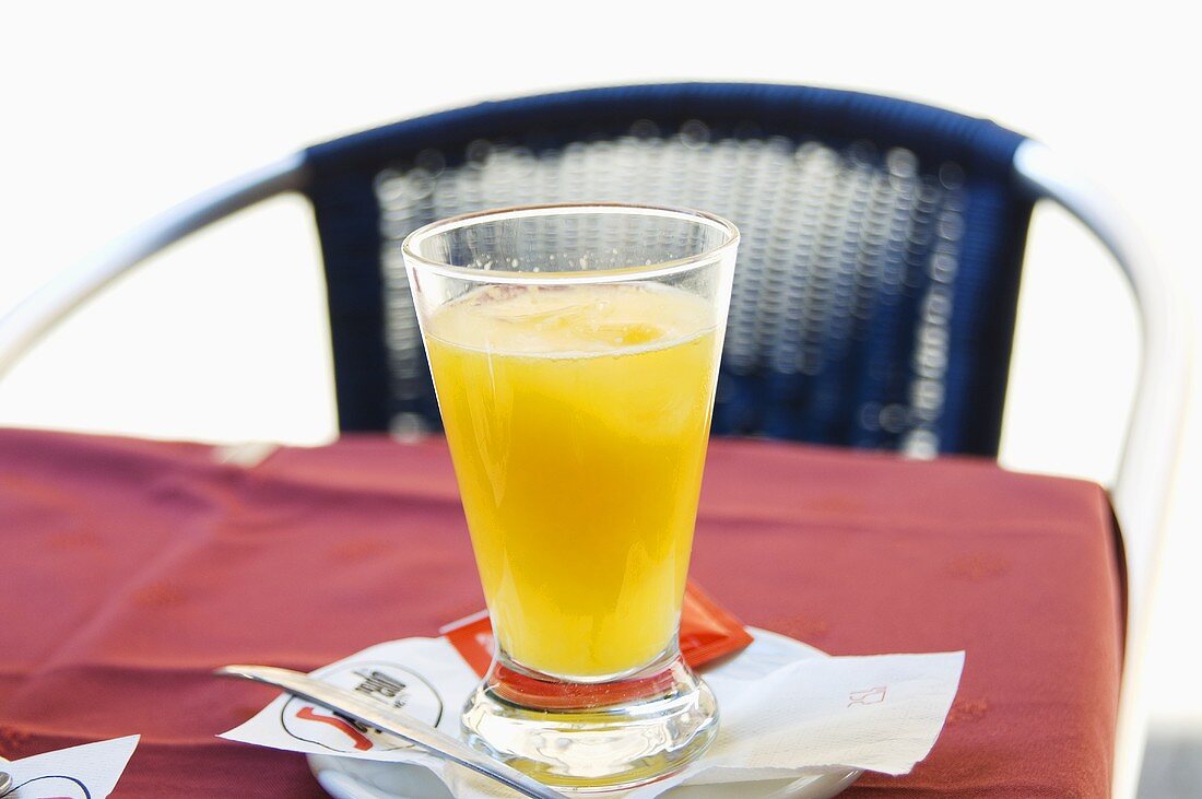 A glass of orange juice on a café table