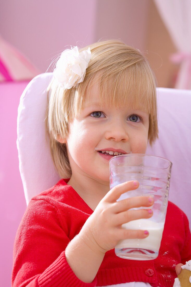 Kleines Mädchen hält ein Glas Milch in der Hand