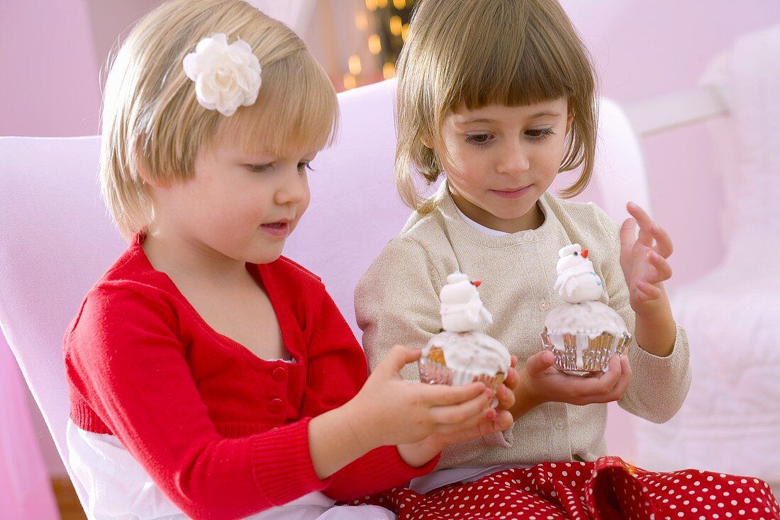 Zwei Mädchen halten Muffins mit Schneemännern in den Händen