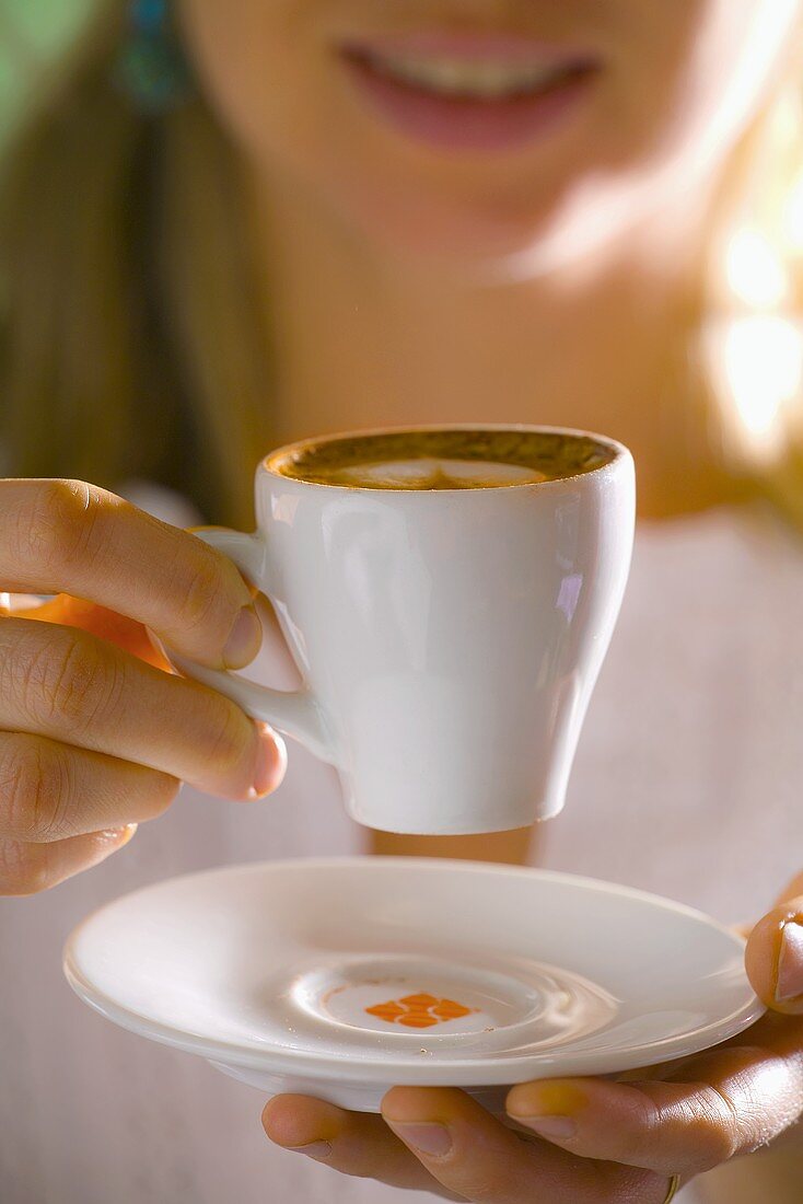 Frau hält eine Tasse Espresso Macchiato