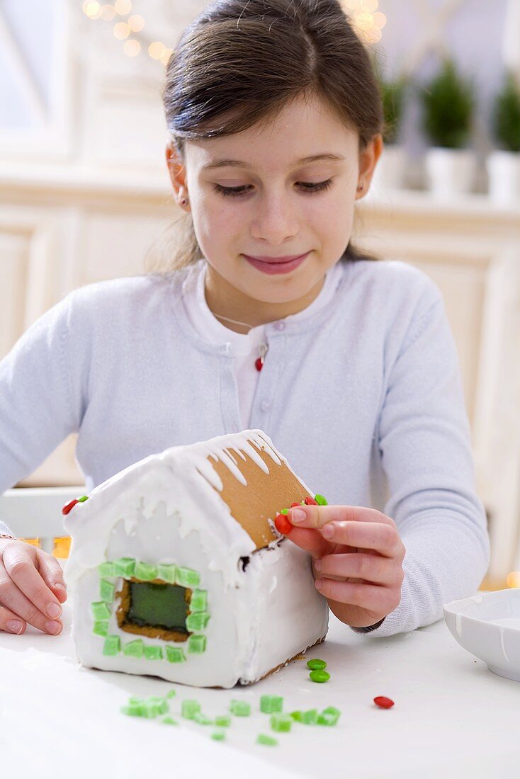 Girl decorating a gingerbread house for Christmas