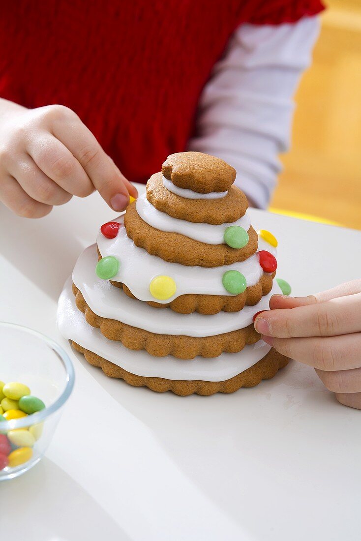 Kinder verzieren Keks-Tannenbäumchen zu Weihnachten