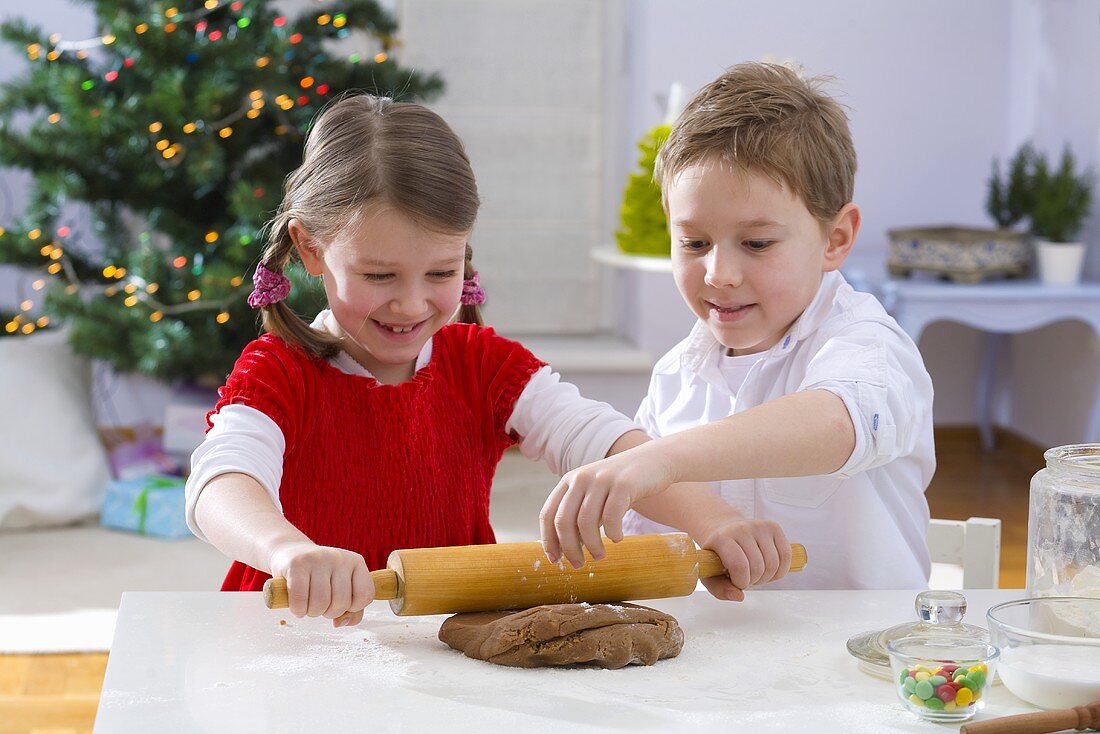 Two children rolling out dough for Christmas biscuits