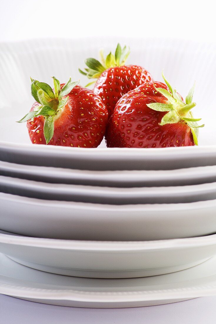 Three strawberries on stacked plates