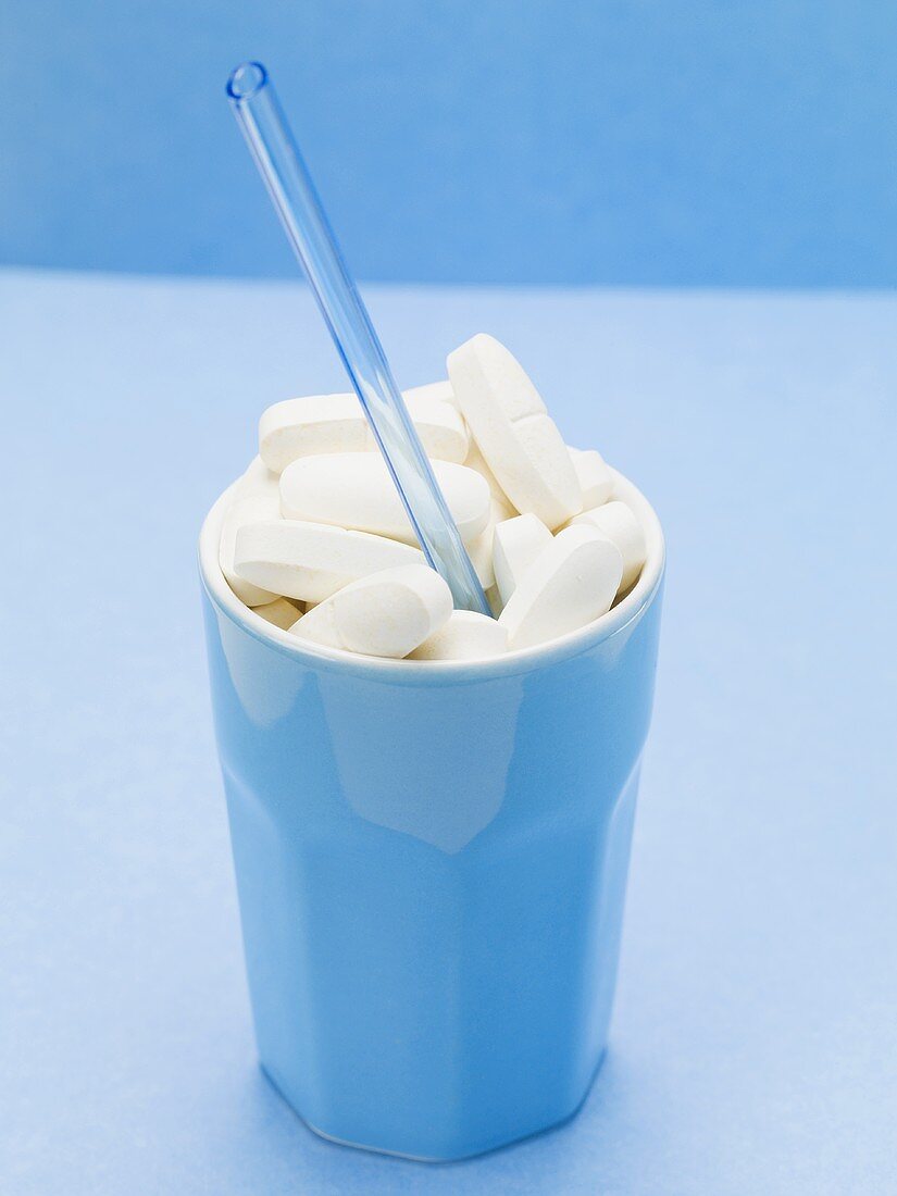 Tablets in a beaker with a straw