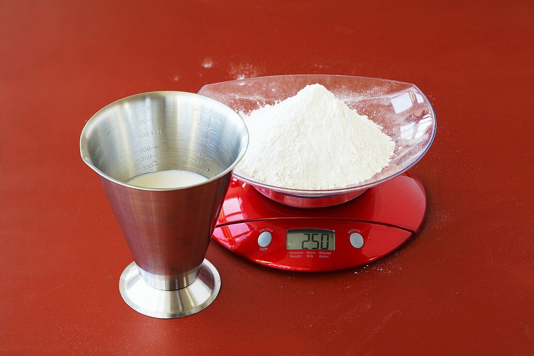 Measuring cup and kitchen scales with flour