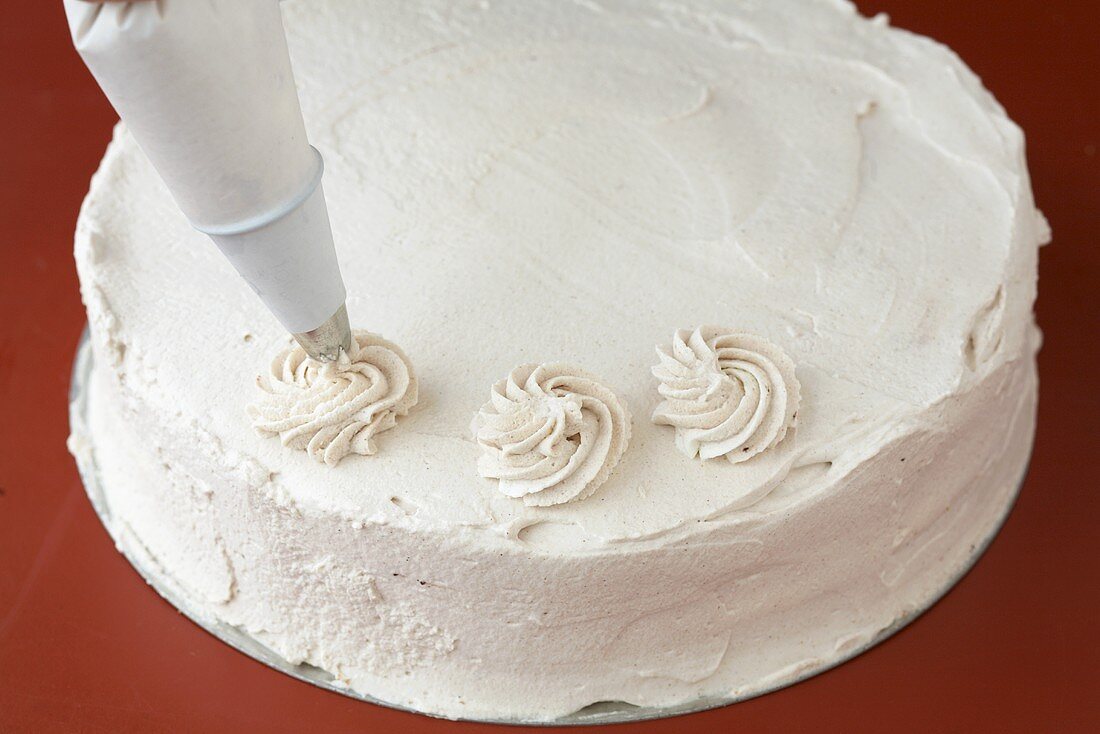 Decorating a cake (piping cream rosettes)