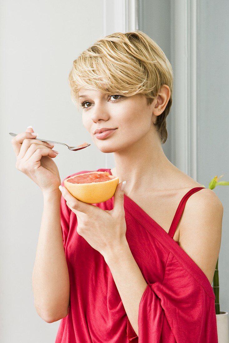 Junge Frau isst Grapefruit mit Löffel