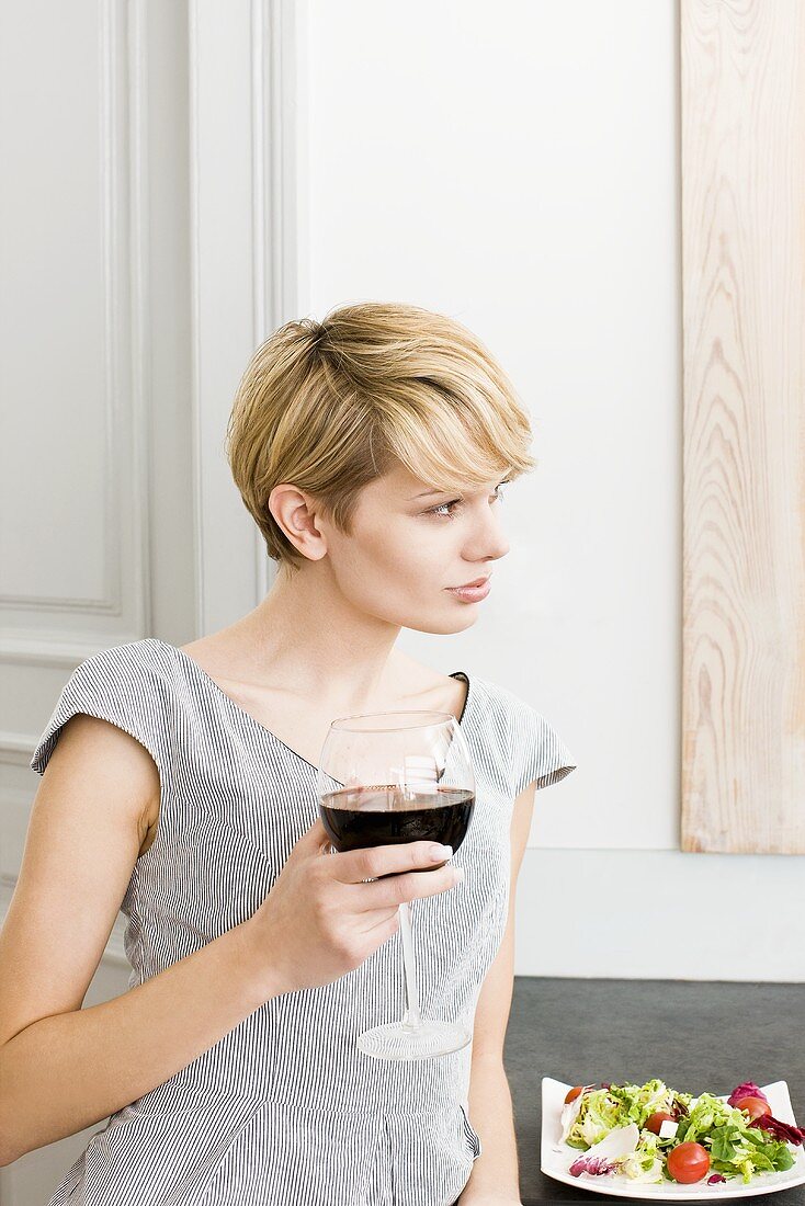 Young woman with a glass of red wine and salad