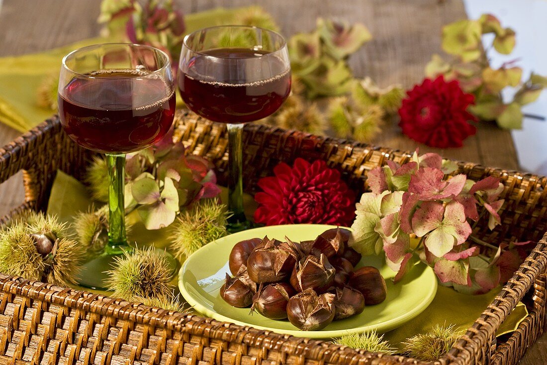 Tablett mit heißen Maronen, Dahlienblüten und Rotwein