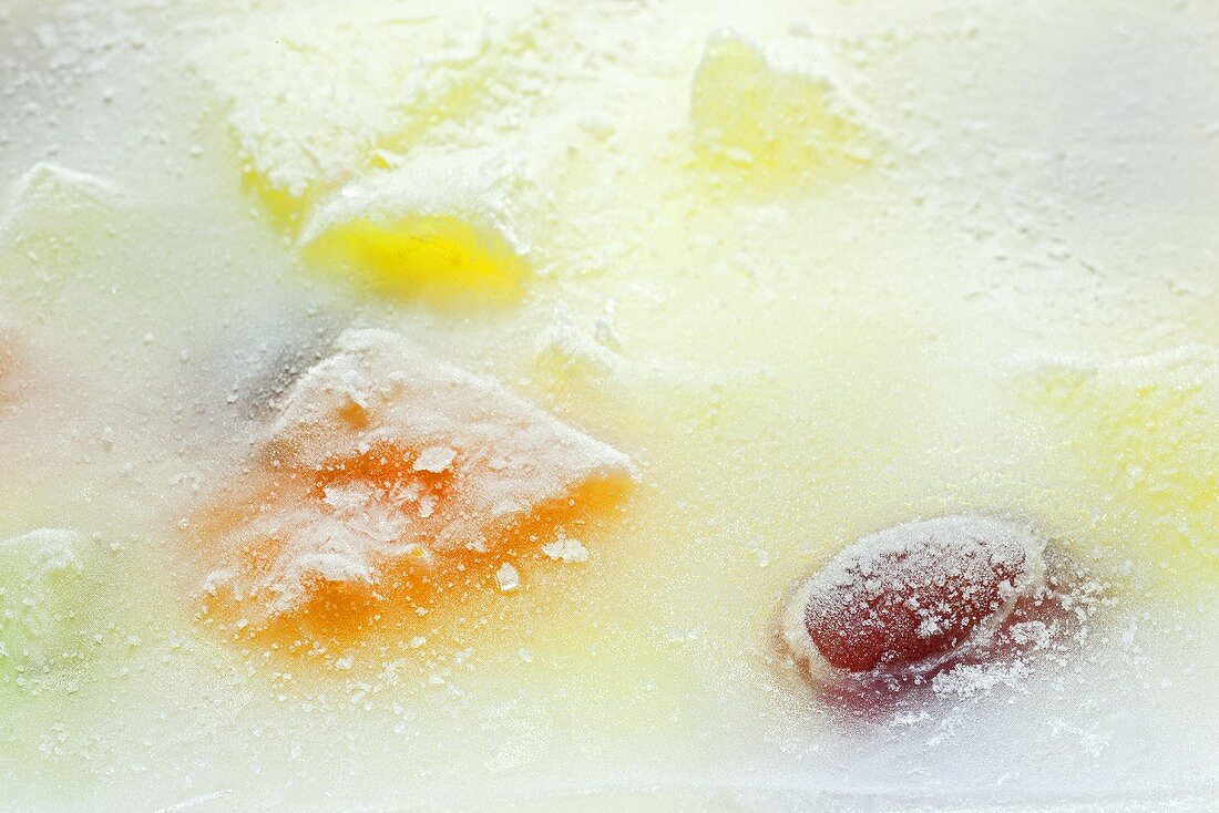 Fruit salad frozen in a block of ice (close-up)