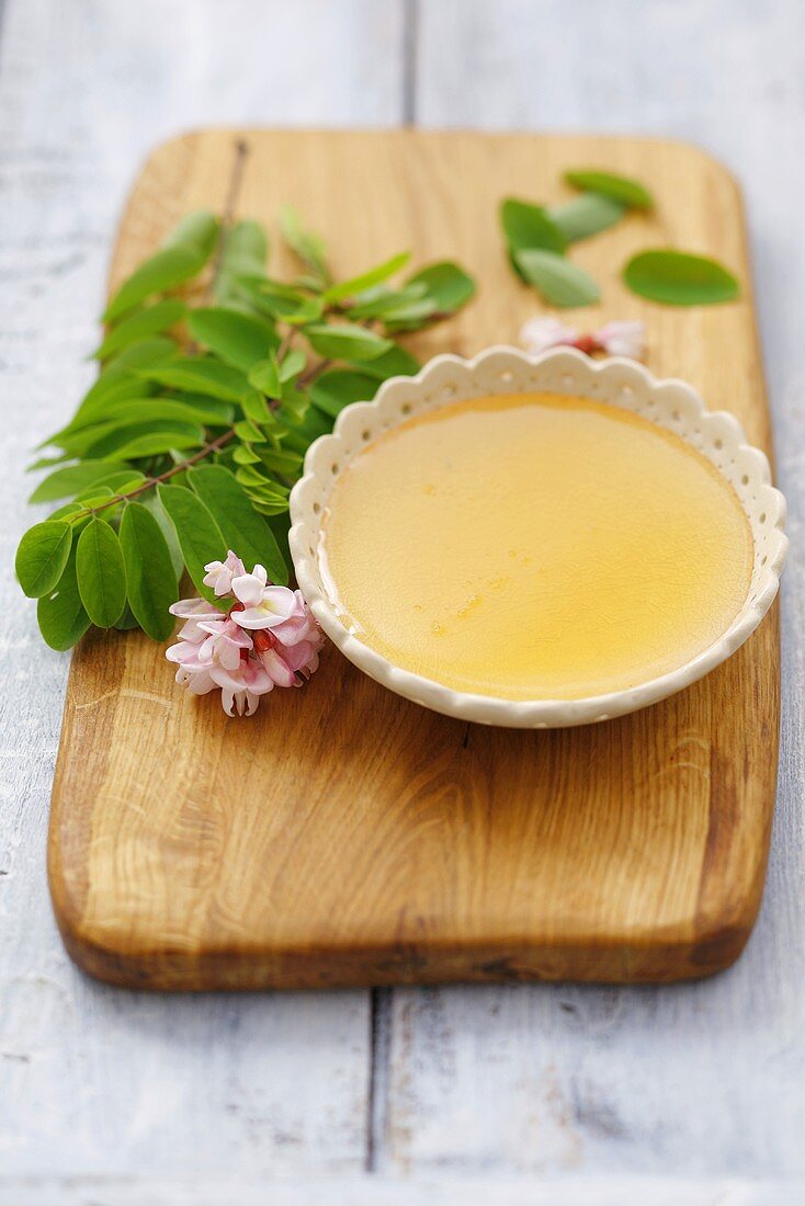 Acacia honey in a small dish with acacia blossom and leaves