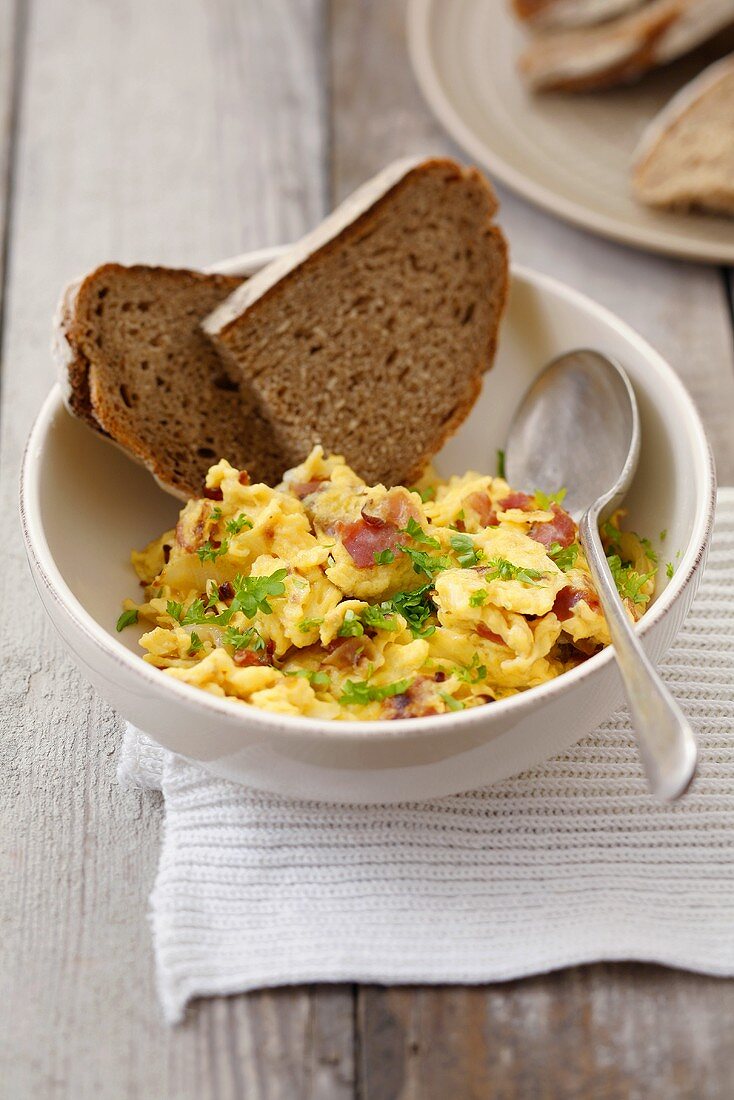 Scrambled egg with ham, parsley and bread