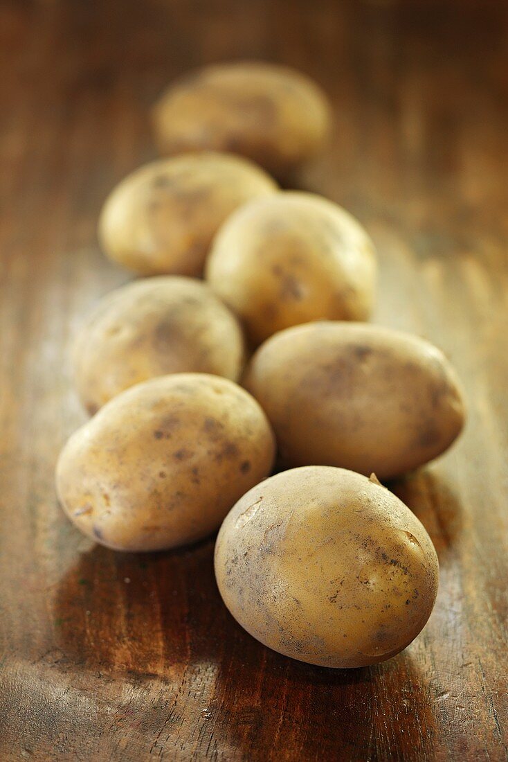 Several potatoes on wooden background