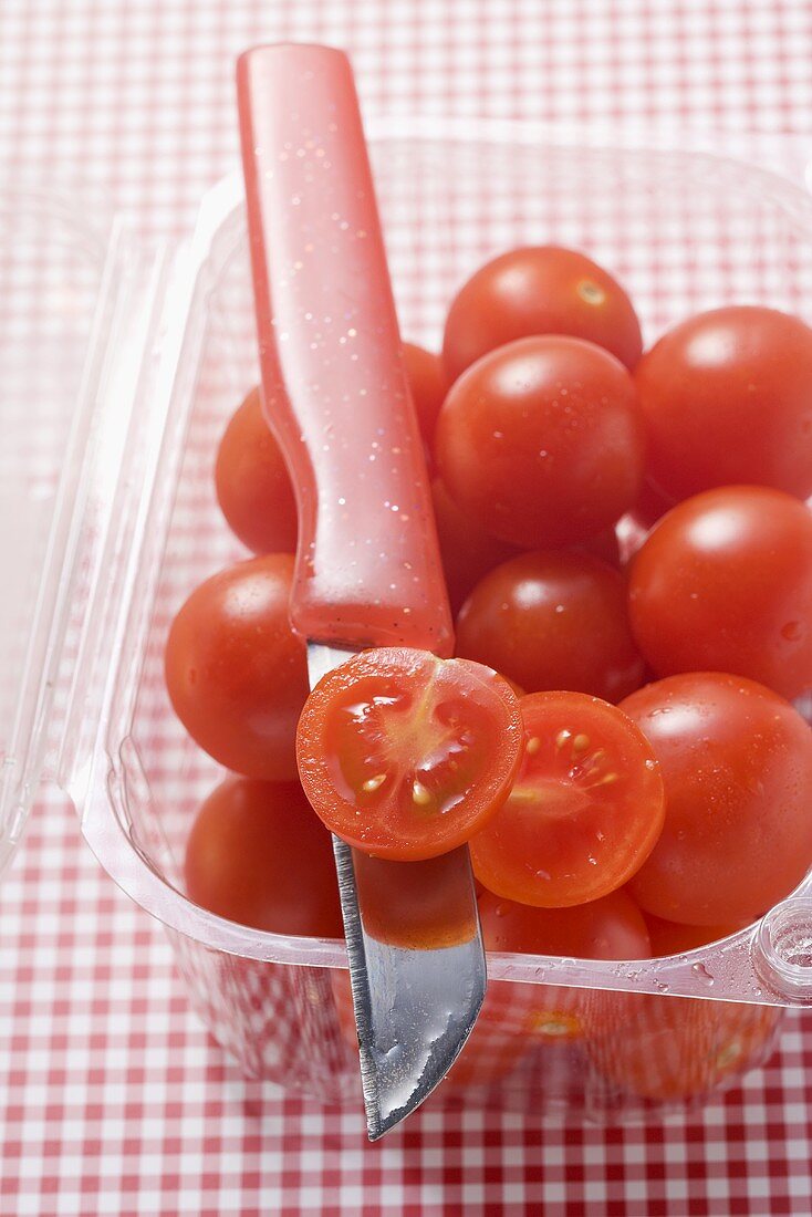 Cocktail tomatoes in plastic punnet with knife