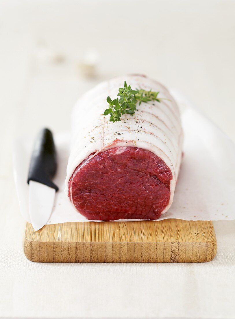 Raw rolled joint of beef wrapped in pork fat