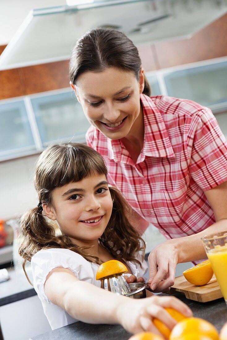 Mutter und Tochter beim Orangen auspressen in der Küche