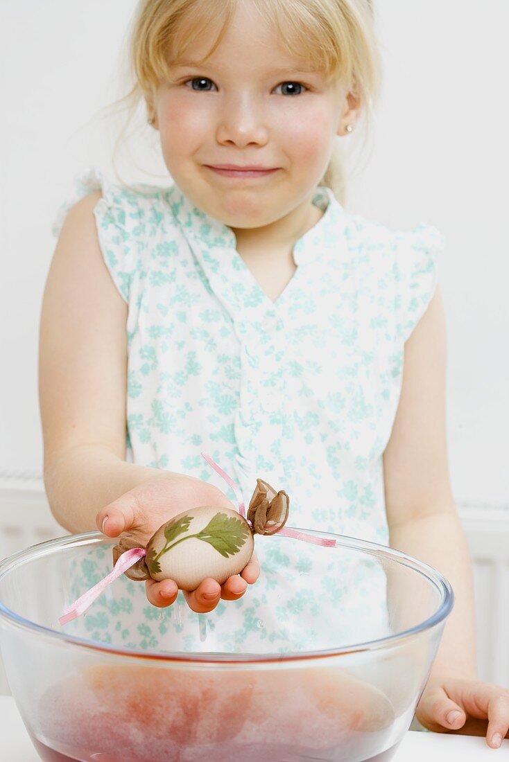 Little girl dyeing Easter egg