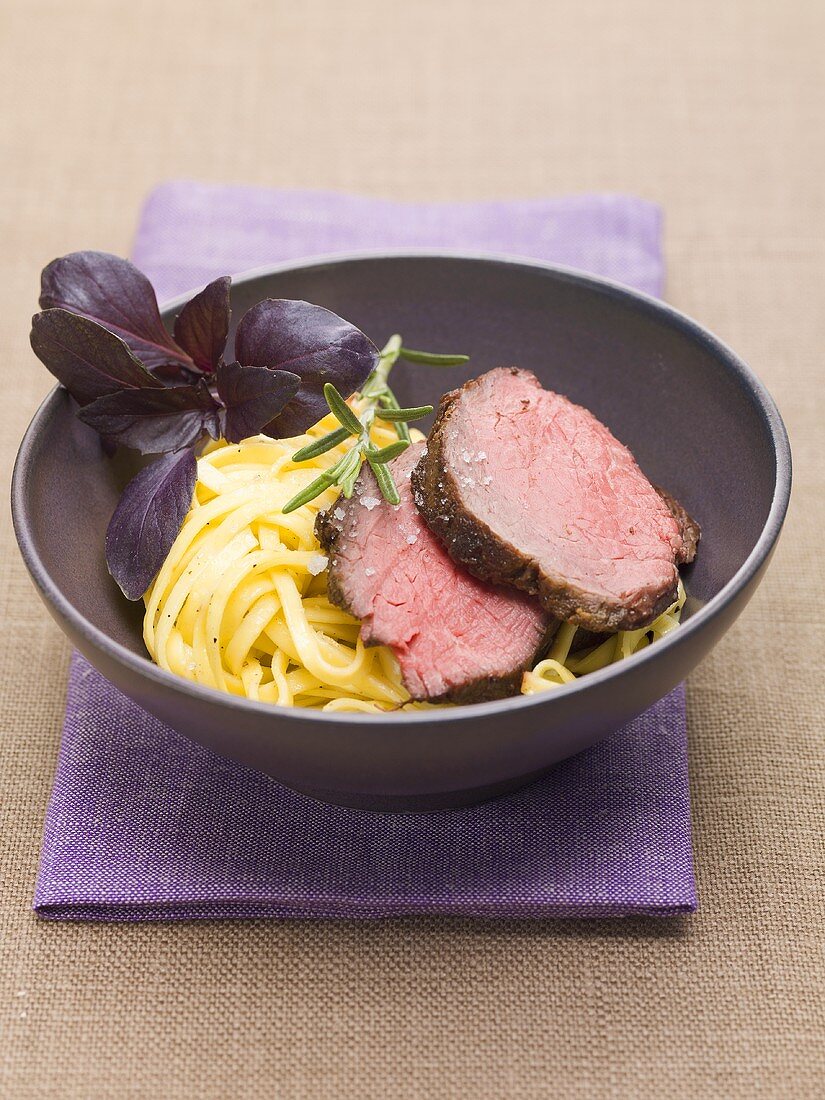Beef fillet with fresh ribbon pasta and red basil