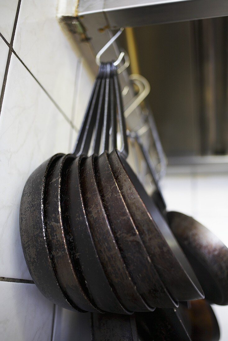 Eisenpfannen hängen am Haken in einer Küche