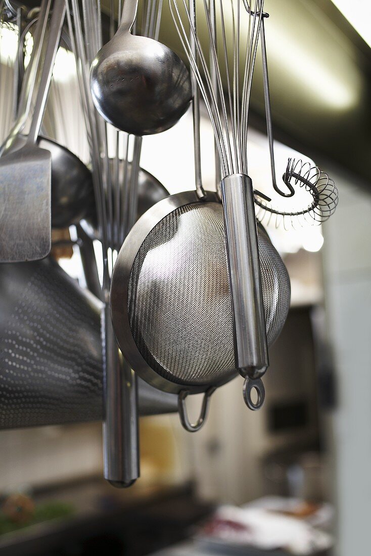 Various kitchen tools hanging on hooks in a kitchen