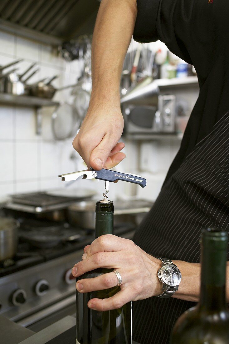 Kellner öffnet Rotwein in einer Restaurantküche