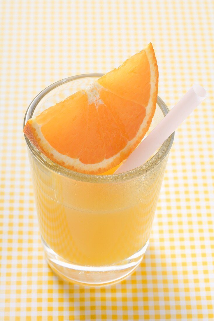 Orange juice with wedge of orange and straw