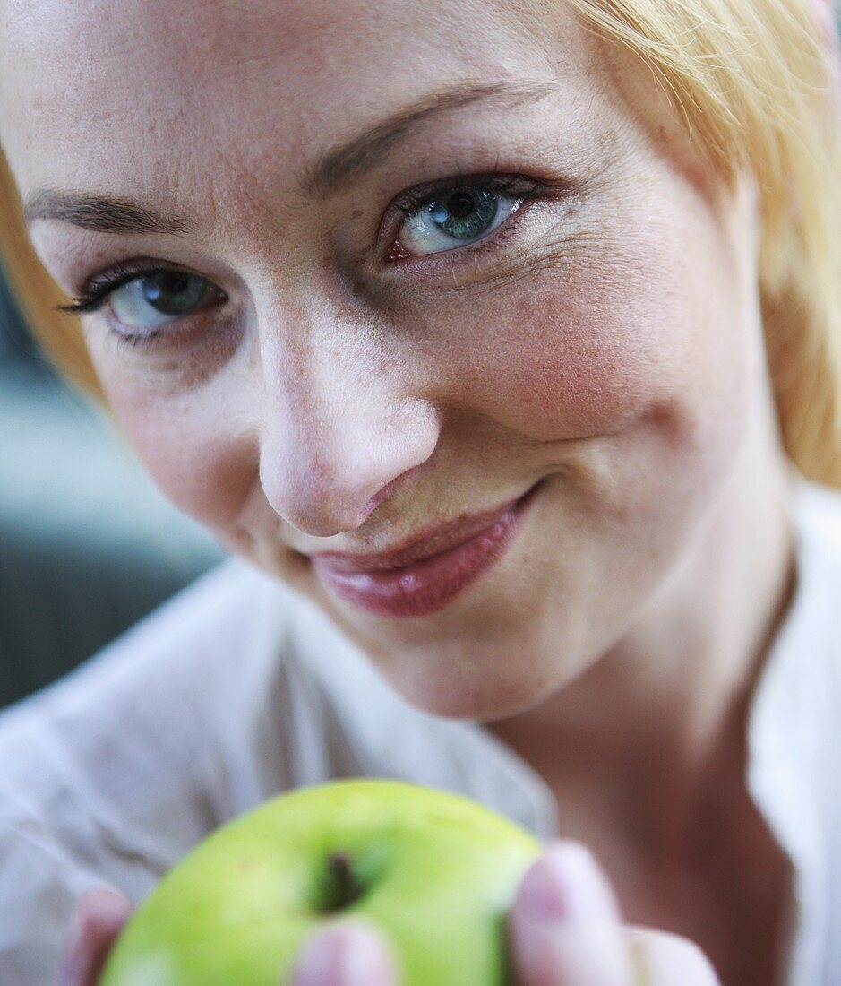 Junge Frau mit grünem Apfel in der Hand