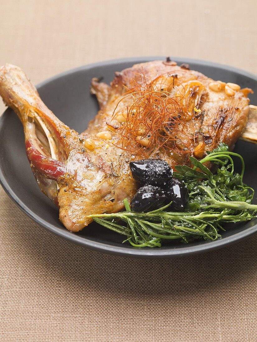 Duck leg with herbs, olives and pine nuts