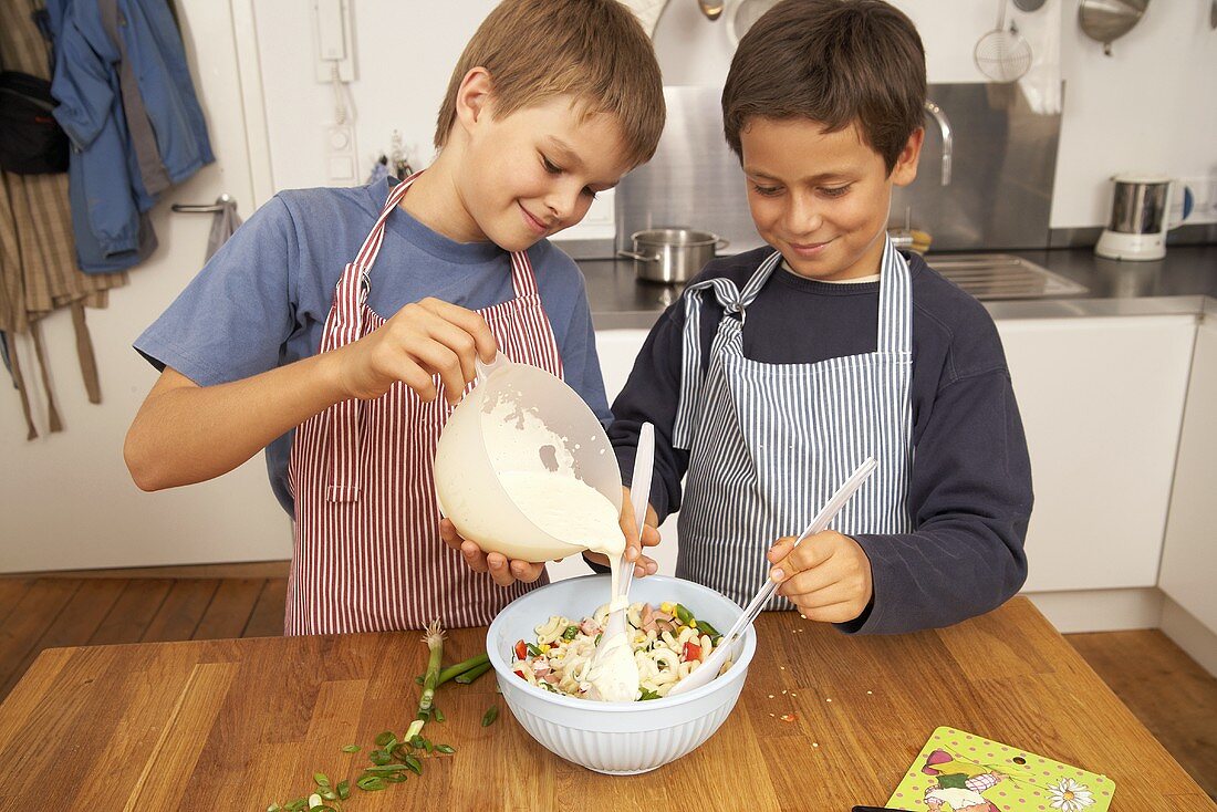 Zwei Jungen bereiten Nudelsalat zu