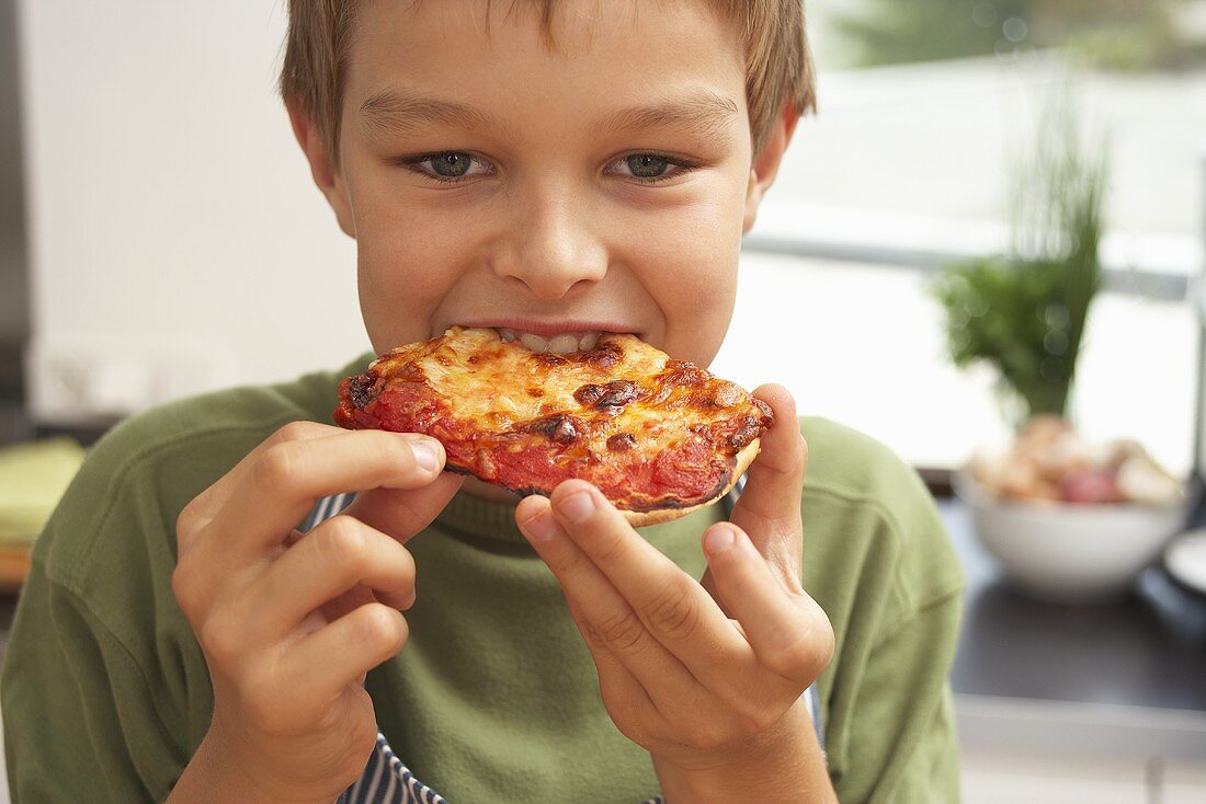 Junge beisst in selbstgemachte Pizza