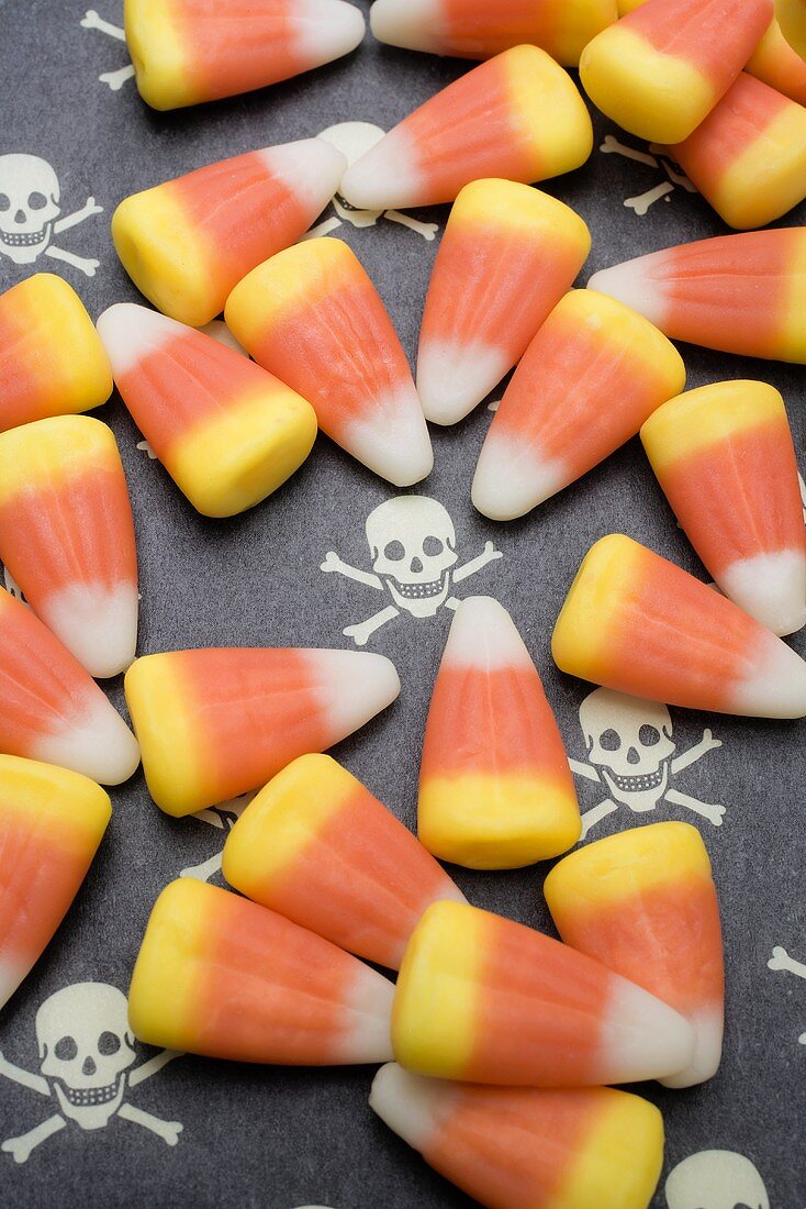Candy Corn auf Untergrund mit Totenköpfen