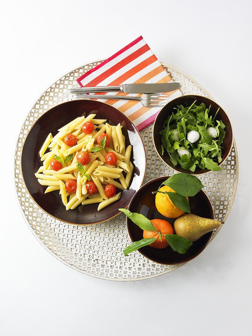Penne mit Tomaten, Rucola-Mozzarella-Salat und Obst