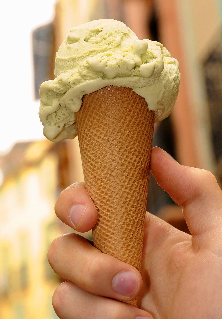 Hand holding a cone of pistachio ice cream