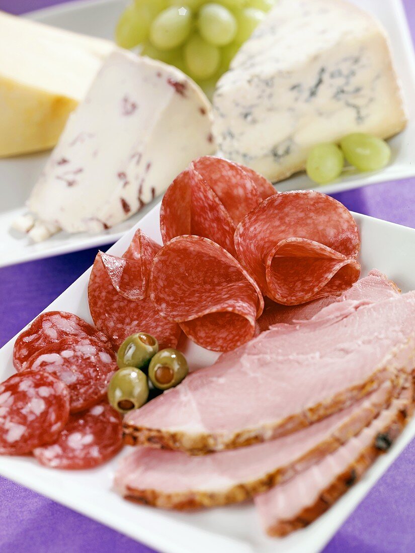 Cold cuts platter with olives and cheese board with grapes