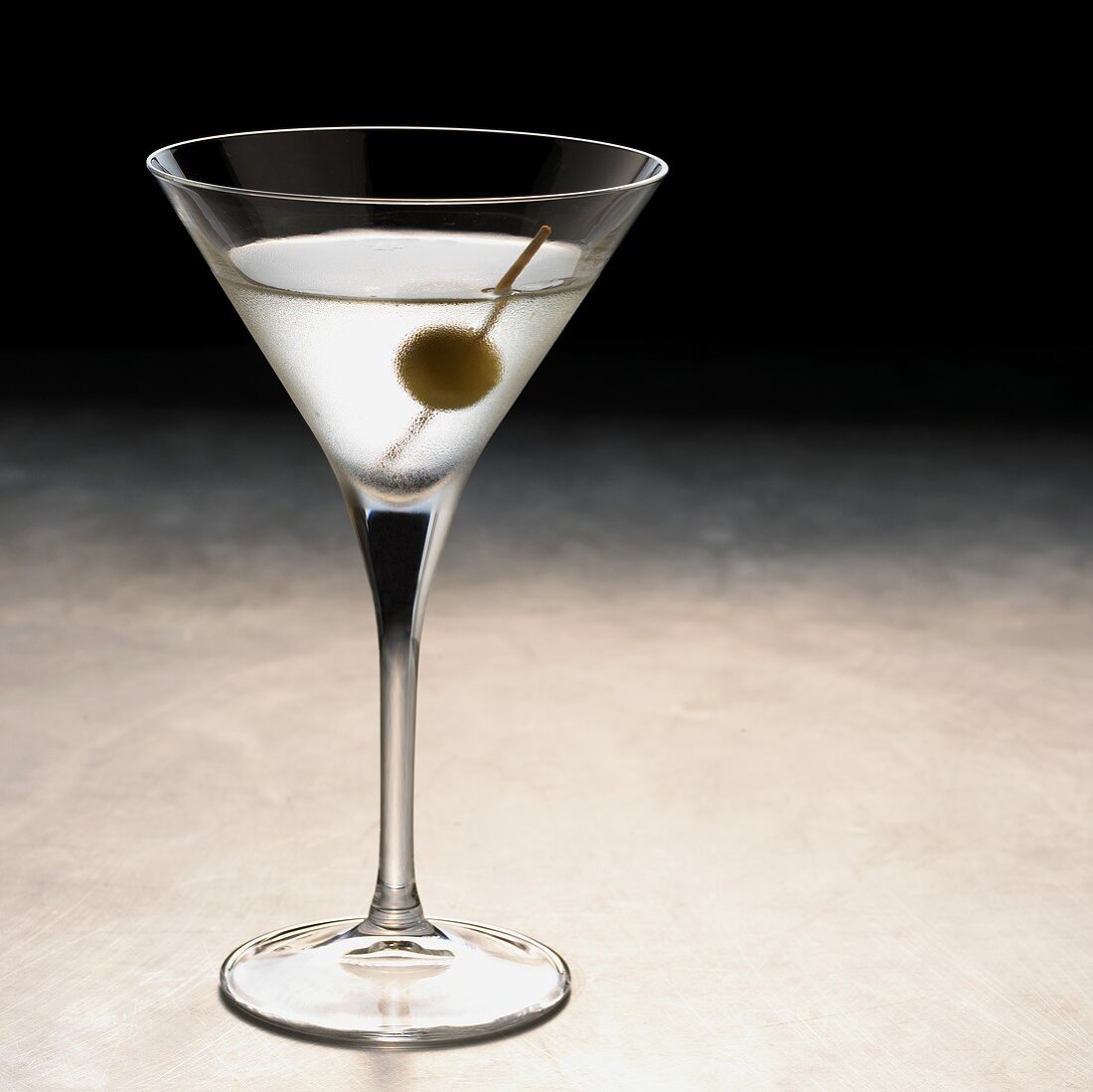 A glass of Martini with a green olive