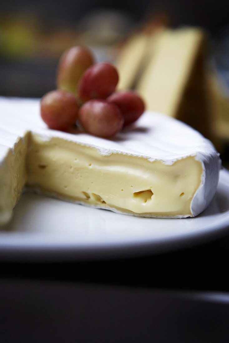 Brie, a section removed, with grapes