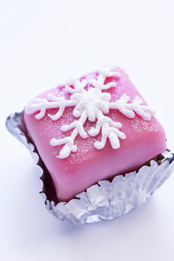 Petit four mit rosa Glasur und Schneeflocke aus Zuckerguss