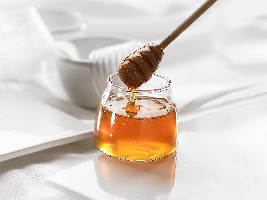 Honig in einem Glas und mit einem Honiglöffel