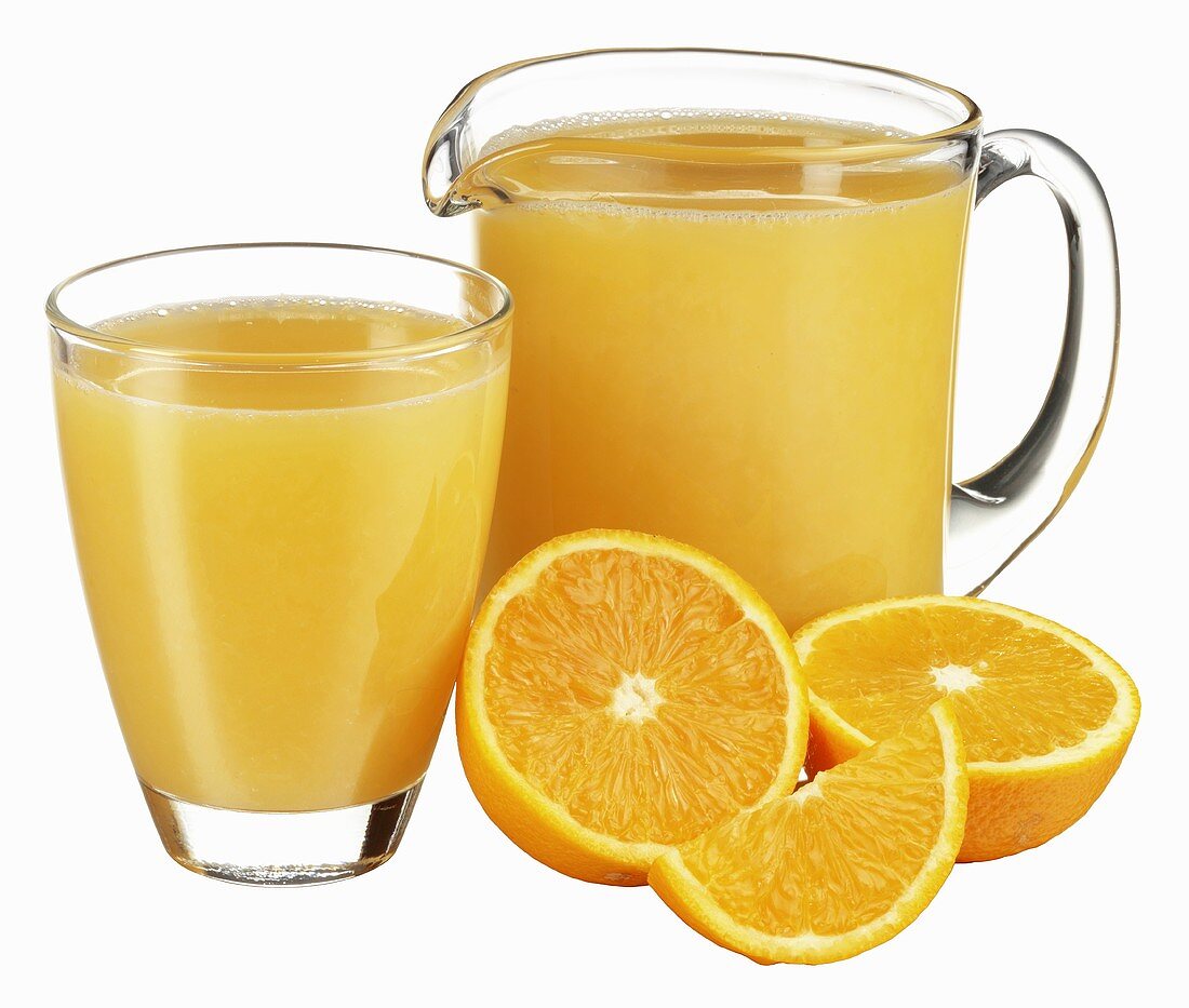 Krug und Glas Orangensaft mit frischen Orangen