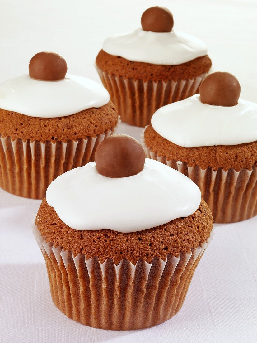 Vier Schoko-Cupcakes mit Zuckerglasur