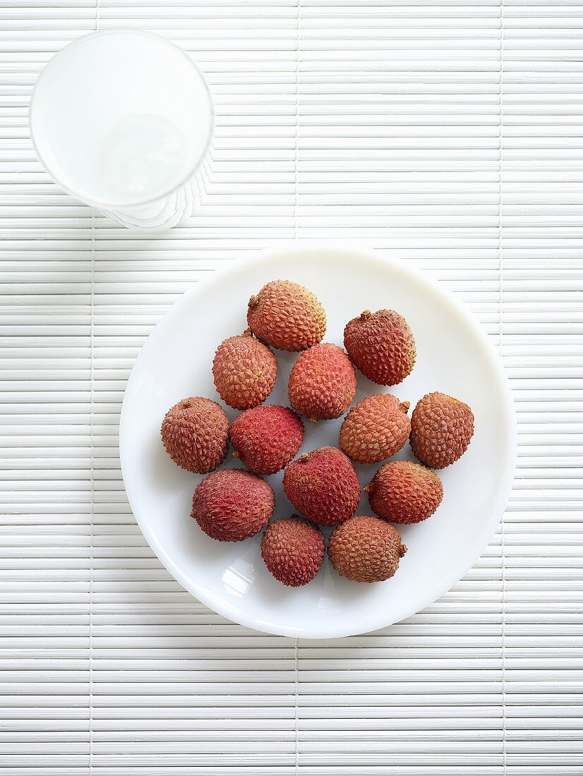 Several unpeeled lychees on plate (overhead view)